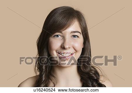Picture - Portrait of a happy young woman with sprinkled lips over colored background. Fotosearch