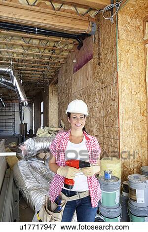 Portrait of a happy young woman with drill at construction site View Large Photo Image Stock Photo - Portrait of a happy young woman with drill at construction site. Fotosearch