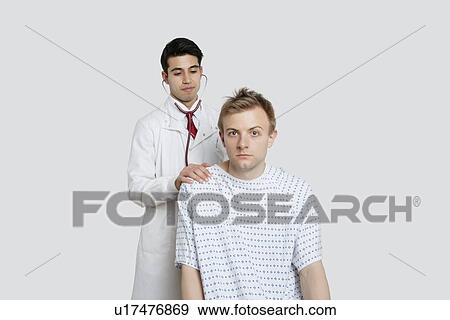 Stock Photo - Portrait of a male patient being treated by an Indian doctor. Fotosearch
