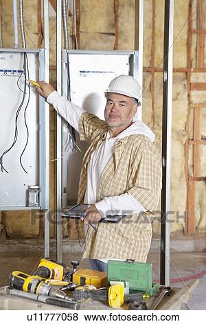 Portrait of a mature male construction worker checking electric meters at construction site View Large Photo Image Stock Photo - Portrait of a mature male construction worker checking electric meters at construction site. Fotosearch