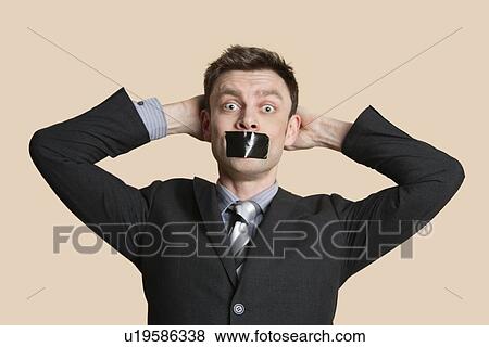 Portrait of a mid adult business professional staring with hands behind head and tape on mouth over colored background View Large Photo Image Stock Photo - Portrait of a mid adult business professional staring with hands behind head and tape on mouth over colored background. Fotosearch