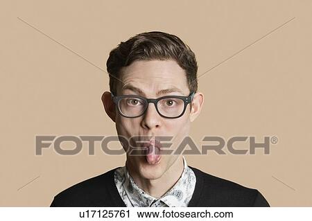 Portrait of a mid adult man sticking out tongue over colored background View Large Photo Image Stock Image - Portrait of a mid adult man sticking out tongue over colored background. Fotosearch