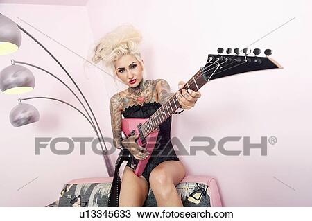 Portrait of a tattooed woman wearing corset while holding guitar against wall View Large Photo Image Stock Image - Portrait of a tattooed woman wearing corset while holding guitar against wall. Fotosearch
