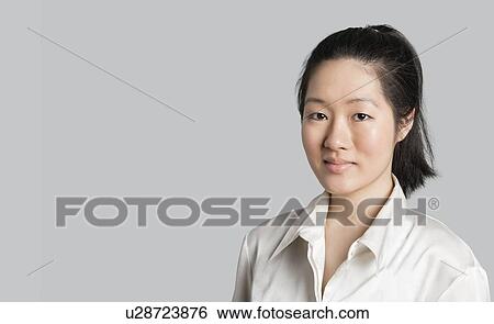 Stock Photograph - Portrait of a young Asian female doctor over gray background. Fotosearch