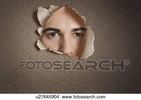 Portrait of a young Caucasian man peeking from ripped paper hole View Large Photo Image Picture - Portrait of a young Caucasian man peeking from ripped paper hole. Fotosearch