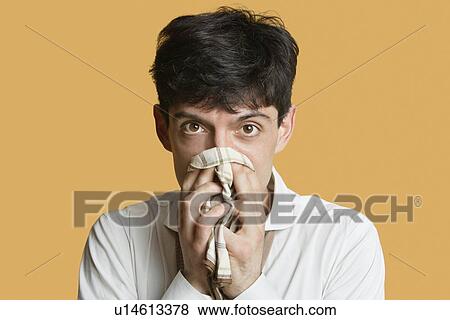 Portrait of a young man blowing nose over colored background View Large Photo Image Stock Photo - Portrait of a young man blowing nose over colored background. Fotosearch