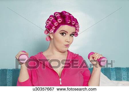 Portrait of a young woman exercising with dumbbell View Large Photo Image Stock Photo - Portrait of a young woman exercising with dumbbell. Fotosearch