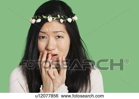 Stock Photograph - Portrait of a young woman expressing fear and anxiety over green background. Fotosearch