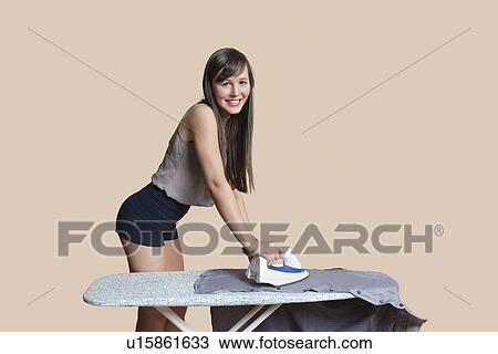 Portrait of a young woman ironing shirt over colored background View Large Photo Image Stock Image - Portrait of a young woman ironing shirt over colored background. Fotosearch
