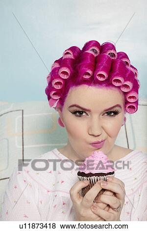 Portrait of a young woman making face while holding cupcake View Large Photo Image Stock Photo - Portrait of a young woman making face while holding cupcake. Fotosearch