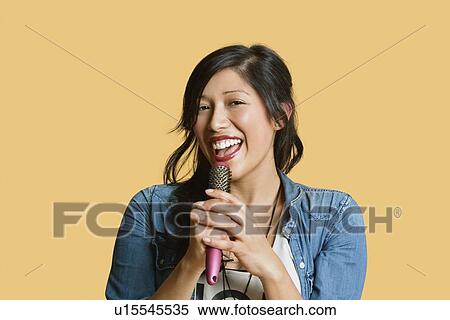 Portrait of a young woman singing into a hairbrush over colored background View Large Photo Image Stock Photography - Portrait of a young woman singing into a hairbrush over colored background. Fotosearch