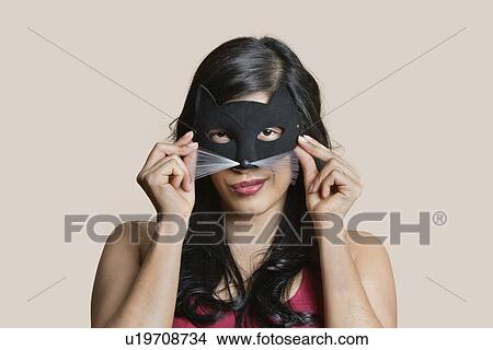 Picture - Portrait of a young woman wearing eye mask over colored background. Fotosearch