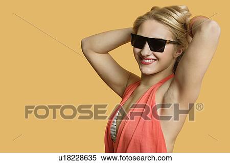 Portrait of a young woman wearing sunglasses with hands in hair over colored background View Large Photo Image Stock Photography - Portrait of a young woman wearing sunglasses with hands in hair over colored background. Fotosearch