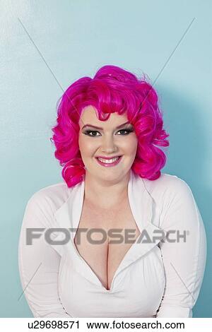 Stock Image - Portrait of a young woman with pink dyed hair over colored background. Fotosearch