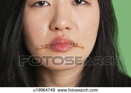Stock Photo - Portrait of a young woman with chocolate stains around her lips. Fotosearch