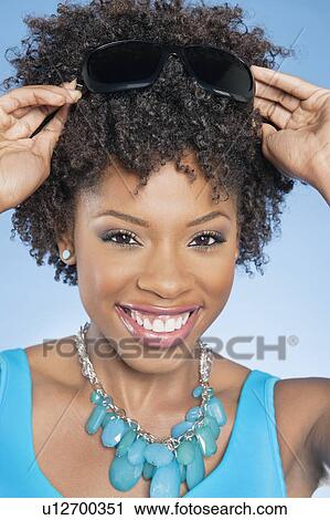 Portrait of African American woman adjusting sunglasses over colored background View Large Photo Image Stock Image - Portrait of African American woman adjusting sunglasses over colored background. Fotosearch
