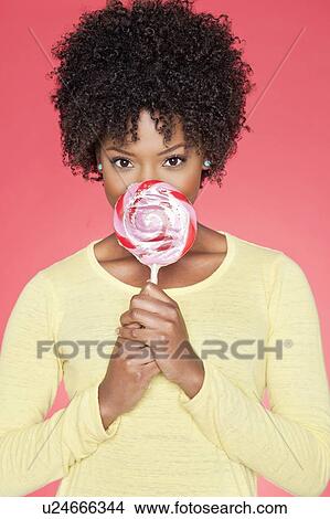Portrait of an African American woman holding candy over colored background View Large Photo Image Picture - Portrait of an African American woman holding candy over colored background. Fotosearch