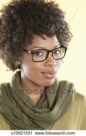 Stock Image - Portrait of an African American woman wearing glasses with a stole round her neck over colored background. Fotosearch