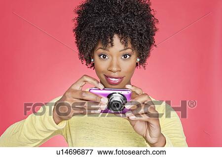 Portrait of an African American woman holding a camera over colored background View Large Photo Image Stock Photo - Portrait of an African American woman holding a camera over colored background. Fotosearch