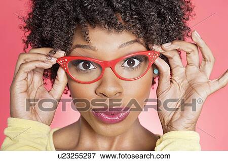 Stock Photo - Portrait of an African American woman wearing retro style glasses over colored background. Fotosearch