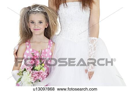 Stock Photo - Portrait of beautiful bridesmaid holding flower bouquet standing next to bride. Fotosearch