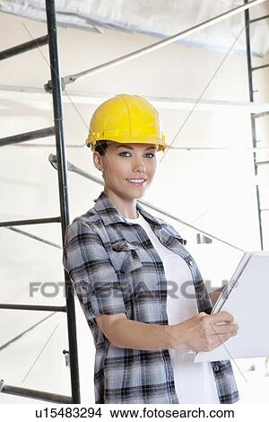 Portrait of beautiful mid adult architect wearing hardhat with blueprints View Large Photo Image Picture - Portrait of beautiful mid adult architect wearing hardhat with blueprints. Fotosearch