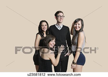 Stock Image - Portrait of beautiful women surrounding mid adult man over colored background. Fotosearch