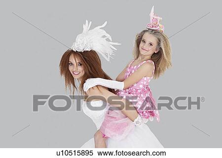 Portrait of beautiful young bride giving piggyback ride to bridesmaid over gray background View Large Photo Image Stock Photography - Portrait of beautiful young bride giving piggyback ride to bridesmaid over gray background. Fotosearch