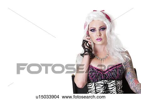 Portrait of beautiful young woman wearing wig while listening to mobile phone over white background View Large Photo Image Picture - Portrait of beautiful young woman wearing wig while listening to mobile phone over white background. Fotosearch