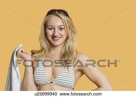 Stock Image - Portrait of beautiful young woman wearing bikini over colored background. Fotosearch