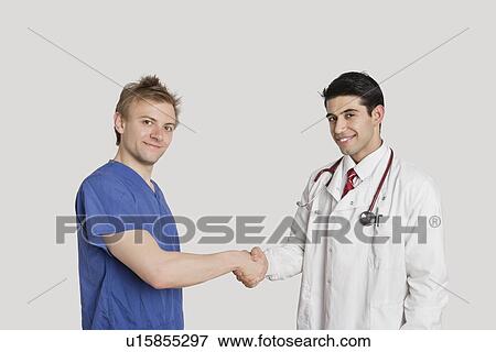 Portrait of doctor and male nurse shaking hands over gray background View Large Photo Image Stock Photo - Portrait of doctor and male nurse shaking hands over gray background. Fotosearch