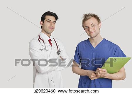 Stock Image - Portrait of doctor standing with coworker over light gray background. Fotosearch