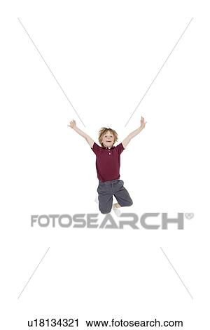 Stock Image - Portrait of elementary boy jumping in air with arms raised over white background. Fotosearch