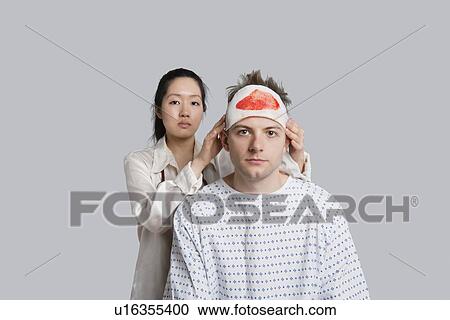 Portrait of female doctor examining injured male patient View Large Photo Image Stock Image - Portrait of female doctor examining injured male patient. Fotosearch