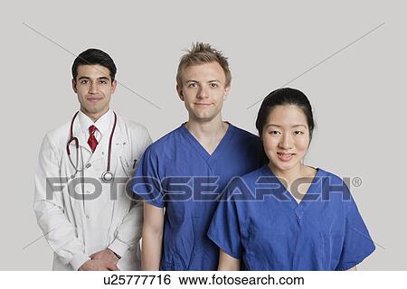 Stock Photograph - Portrait of happy medical team standing over gray background. Fotosearch