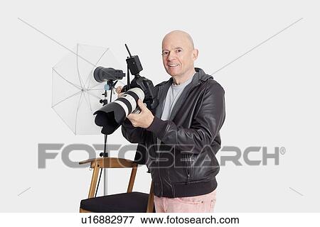 Portrait of happy senior man with camera standing in photographer's studio View Large Photo Image Stock Photo - Portrait of happy senior man with camera standing in photographer's studio. Fotosearch