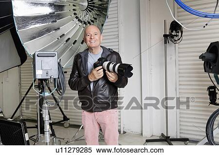 Portrait of happy senior photographer with camera in studio View Large Photo Image Stock Photography - Portrait of happy senior photographer with camera in studio. Fotosearch