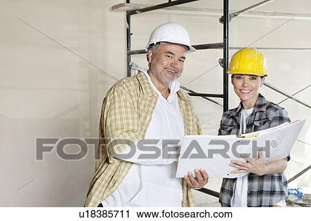 Portrait of happy team of architect with paper documents at construction site View Large Photo Image Stock Image - Portrait of happy team of architect with paper documents at construction site. Fotosearch