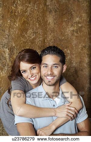 Portrait of happy young woman hugging man from behind View Large Photo Image Stock Photo - Portrait of happy young woman hugging man from behind. Fotosearch