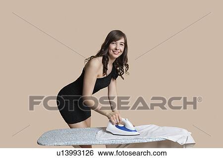 Portrait of happy young woman ironing shirt over colored background View Large Photo Image Stock Photograph - Portrait of happy young woman ironing shirt over colored background. Fotosearch