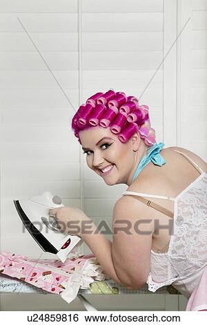 Stock Photograph - Portrait of happy young woman with iron. Fotosearch
