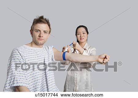 Picture - Portrait of male patient with doctor preparing him for a blood test. Fotosearch