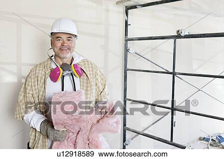 Stock Photo - Portrait of mature man holding sponge with dust mask in neck. Fotosearch