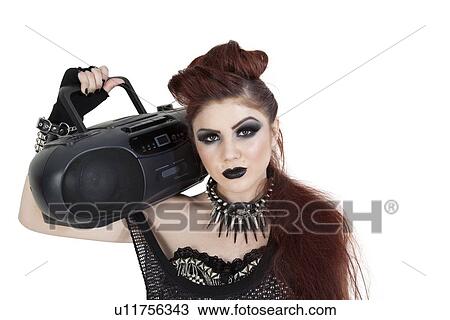 Stock Image - Portrait of punk woman holding boom box on shoulder over white background. Fotosearch