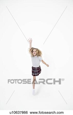 Portrait of school girl jumping with hand raised over white background View Large Photo Image Stock Photograph - Portrait of school girl jumping with hand raised over white background. Fotosearch