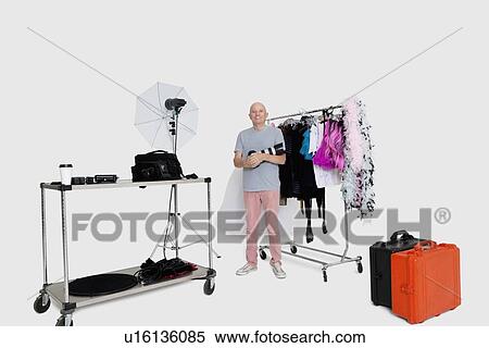 Portrait of senior photographer standing in front of clothes rack in studio View Large Photo Image Stock Photography - Portrait of senior photographer standing in front of clothes rack in studio. Fotosearch