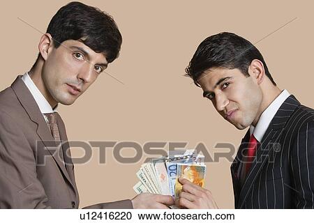 Portrait of young businessmen showing Euros over colored background View Large Photo Image Stock Image - Portrait of young businessmen showing Euros over colored background. Fotosearch