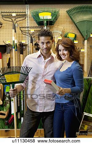 Stock Photo - Portrait of young couple with gardening claw in store. Fotosearch