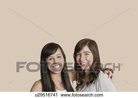 Stock Image - Portrait of young female friends over colored background. Fotosearch