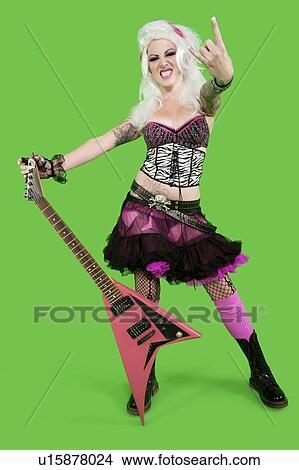 Portrait of young punk woman holding guitar with rock & roll hand sign over green background View Large Photo Image Picture - Portrait of young punk woman holding guitar with rock & roll hand sign over green background. Fotosearch